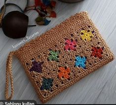 a crocheted pouch sitting on top of a wooden floor next to a pair of glasses