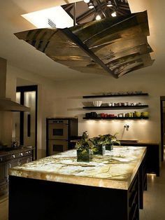 a kitchen with an island counter and lights above the stove top in front of it