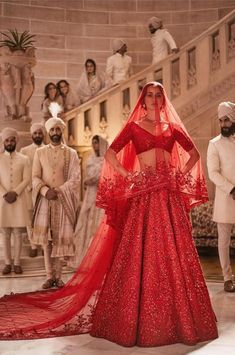 a woman in a red gown standing next to other people