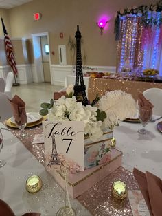 the table is set up for an event with flowers, candles and place cards in front of the eiffel tower