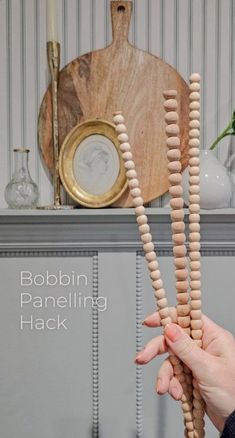 a person holding wooden beads in front of a fireplace mantel with a clock on it