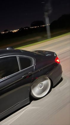 a black car driving down the road at night