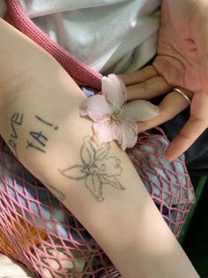 a woman with a flower on her arm and the word love tattooed on her left arm