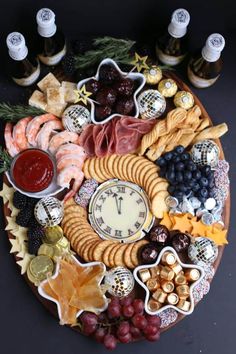 a platter with cheese, crackers, grapes, nuts and meats on it