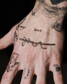 a person's hand with tattoos on it and the word baka written in cursive writing