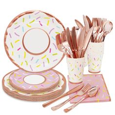 a table set with pink and gold plates, cups, spoons and utensils