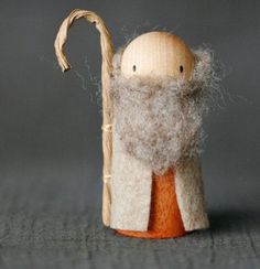 a small wooden doll with a long white beard and orange shirt on it's head