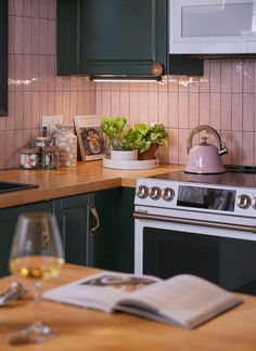 a glass of wine sitting on top of a counter next to an oven and microwave