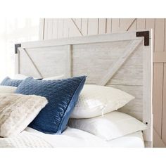 a white bed with blue and white pillows on it's headboard in a bedroom