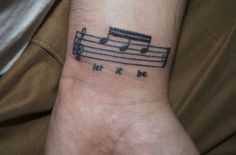 a wrist tattoo with musical notes on it