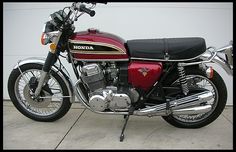 a red and black motorcycle parked in front of a white wall with the words honda on it