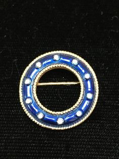 Exquisite Trifari brooch done on brilliant gold plated metal.  Entire circle enameled in a gorgeous royal blue.  Gold roping inside and out and clear chatons dotted in center of enameling.  Measuring 3/4” diameter.  STUNNING! Gold Round Enamel Pin Brooch, Gold Round Enamel Pin, Gold Round Enamel Brooch Pin, Round Enamel Brooches As Gift, Trifari Brooch, Blue Necklace, Drop Necklace, Blue Gold, Costume Jewelry