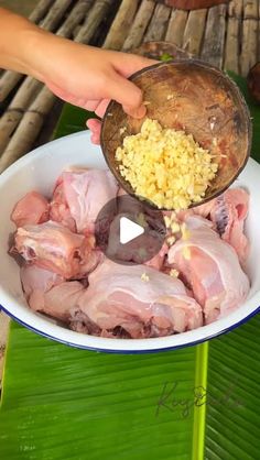 someone is pouring some food into a bowl on a table with banana leaves and other items