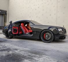 a black car with red leather seats parked in front of a white wall and door