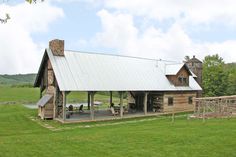 an old log cabin sits in the middle of a grassy field with a picnic table