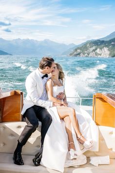 a man and woman sitting on the back of a boat in front of the ocean