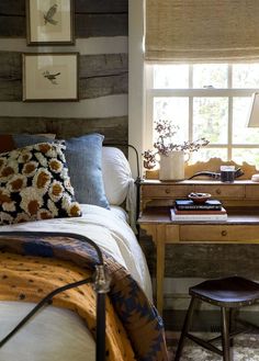 a bed sitting under a window next to a wooden desk