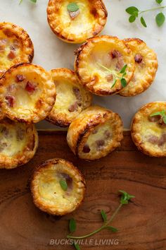 mini quiches with meat and cheese on a cutting board next to fresh herbs, ready to be eaten