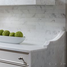 a bowl filled with green balls sitting on top of a counter next to a sink