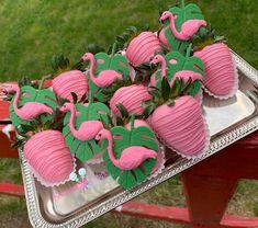 pink and green decorated strawberries in the shape of flamingos on a silver tray