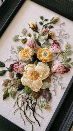 an embroidered floral arrangement in a black frame