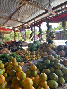 there are many fruits and vegetables on display in the market area, including melons