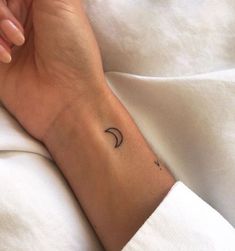 a woman's arm with a small crescent tattoo on the left side of her wrist