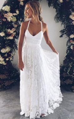 a woman wearing a white dress standing in front of flowers