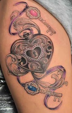 a woman's thigh with an ornate heart and key tattoo on the side of her leg