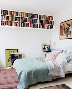 a bed sitting in a bedroom next to a book shelf filled with lots of books