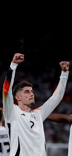 a male soccer player raising his arms in the air