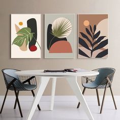 three abstract paintings hang on the wall above a white table in a room with two chairs