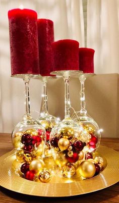 three wine glasses filled with red and gold ornaments on top of a golden platter