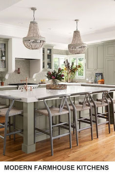 a large kitchen with an island in the middle and chairs at the end, surrounded by green cabinets