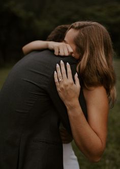 a man and woman hugging each other in the grass