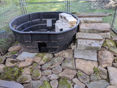 there is a large black tub in the middle of some rocks and stones on the ground