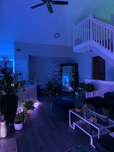 a living room filled with lots of furniture and plants next to a stair case in front of a window