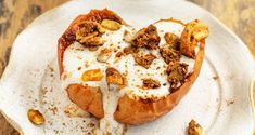 a heart shaped pastry on a plate topped with nuts and cream sauce, sitting on a wooden table