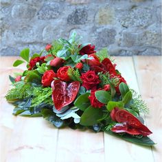 a bouquet of red flowers sitting on top of a wooden table next to a brick wall