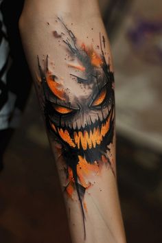 a tattoo with an orange and black design on it's arm that looks like a scary face