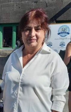 a woman with red hair and white shirt standing in front of a building holding a cell phone