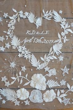 the wedding cake is decorated with white flowers and leaves on wooden boards, which have been cut out to spell their names