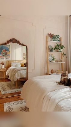 a cat laying on top of a bed next to a large mirror in a bedroom