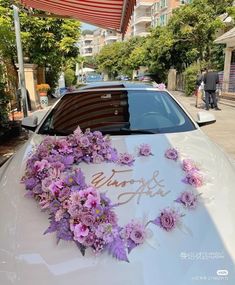 a white car with purple flowers on the hood