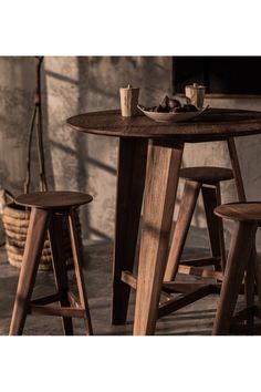 three wooden stools and a table with food on it