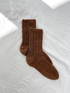 two brown socks laying on top of a white sheet