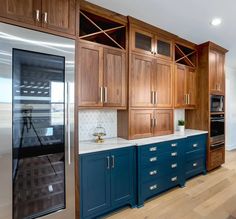 a kitchen with blue cabinets and white counter tops, wood flooring and stainless steel appliances