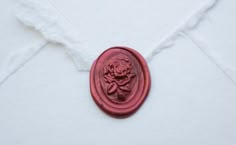 a red wax seal with a rose on it sitting on a piece of white fabric