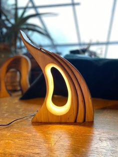 a wooden table with a lamp on top of it and a plant in the background