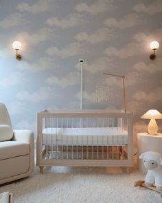 a baby's room with a crib, rocking chair and lamp